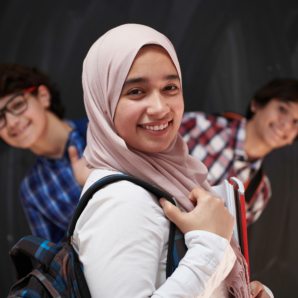 Arabic,Teenagers,,Students,Group,Portrait,Against,Black,Chalkboard,Wearing,Backpack